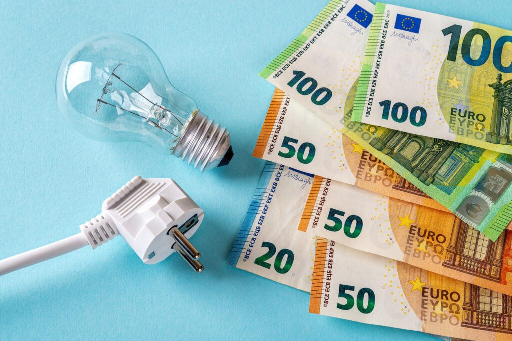 white electric plug, light bulb and euro money banknotes over blue background. increasing of electricity cost.